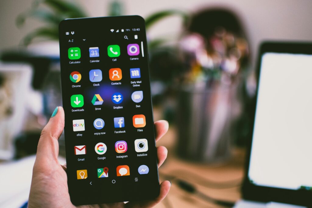 pexels photo 1092644 1092644 A close-up image of a person's hand holding a smartphone displaying various popular apps.
